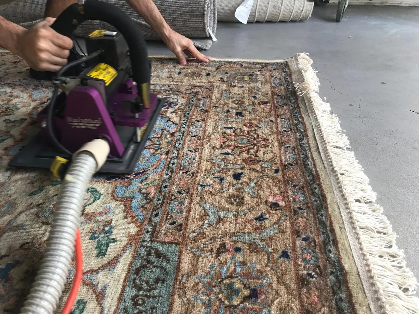 A rug run through the dusting machine to beat out dry grit before washing